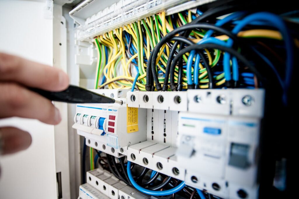 pexels-photo-257736 Hand of electrician working on a circuit breaker panel with colorful wires, ensuring safe electrical connections.
