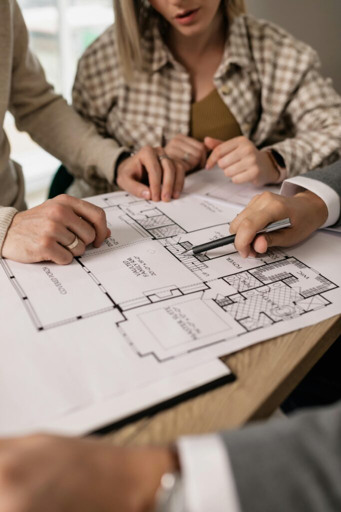 pexels-photo-7641854-7641854 People discuss architectural plans in a real estate planning session, highlighting teamwork.
